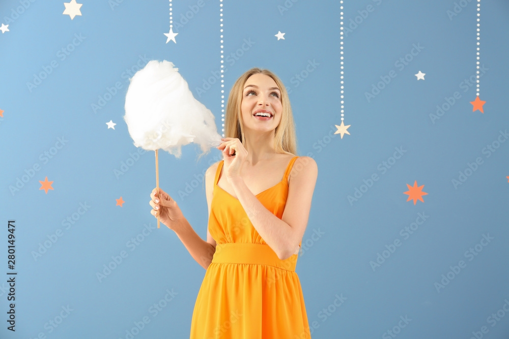 Beautiful woman with cotton candy on color background