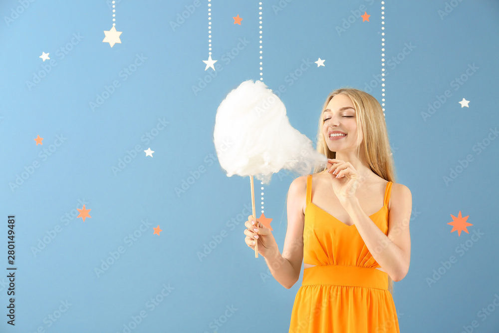 Beautiful woman with cotton candy on color background