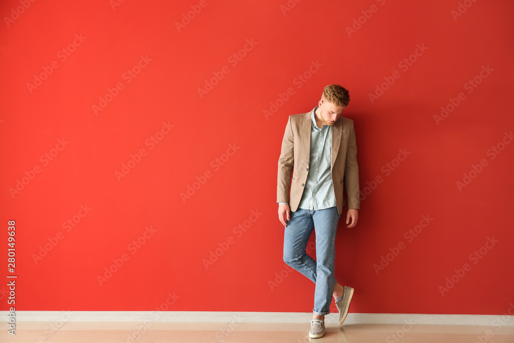 Fashionable young man near color wall