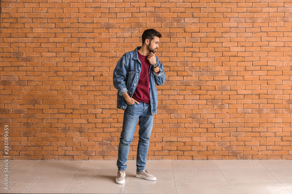 Fashionable young man near brick wall