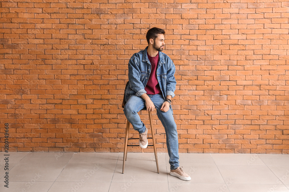 Fashionable young man near brick wall