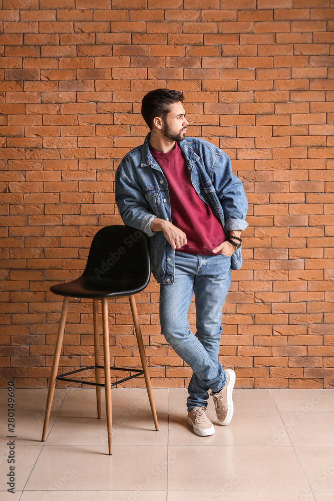 Fashionable young man near brick wall