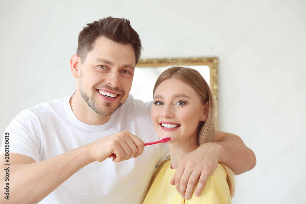 Man cleaning teeth of his wife at home