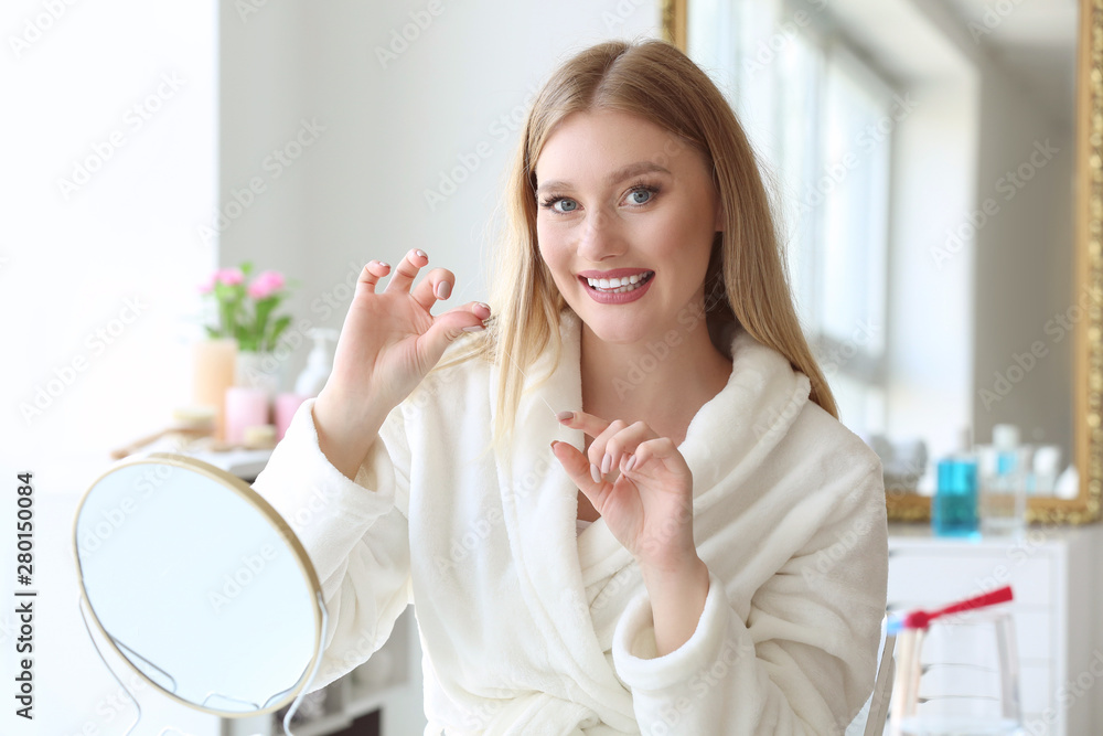 Beautiful woman flossing teeth at home