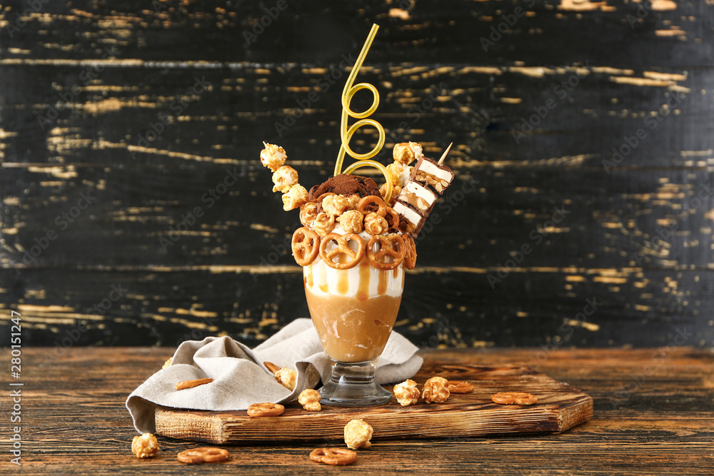 Glass with delicious freak shake on wooden table