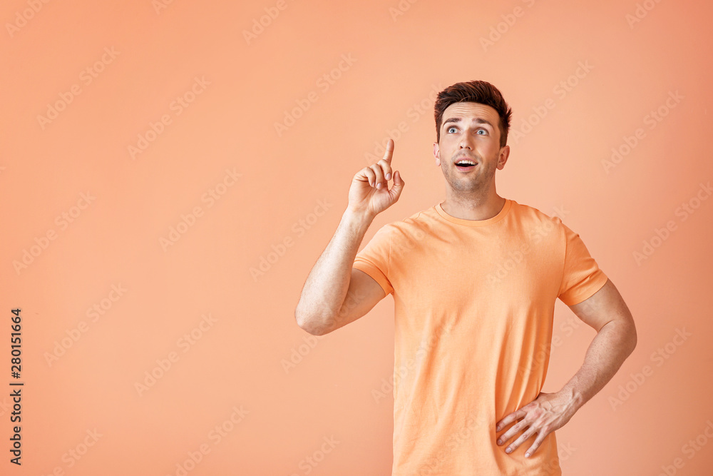 Portrait of handsome man with raised index finger on color background