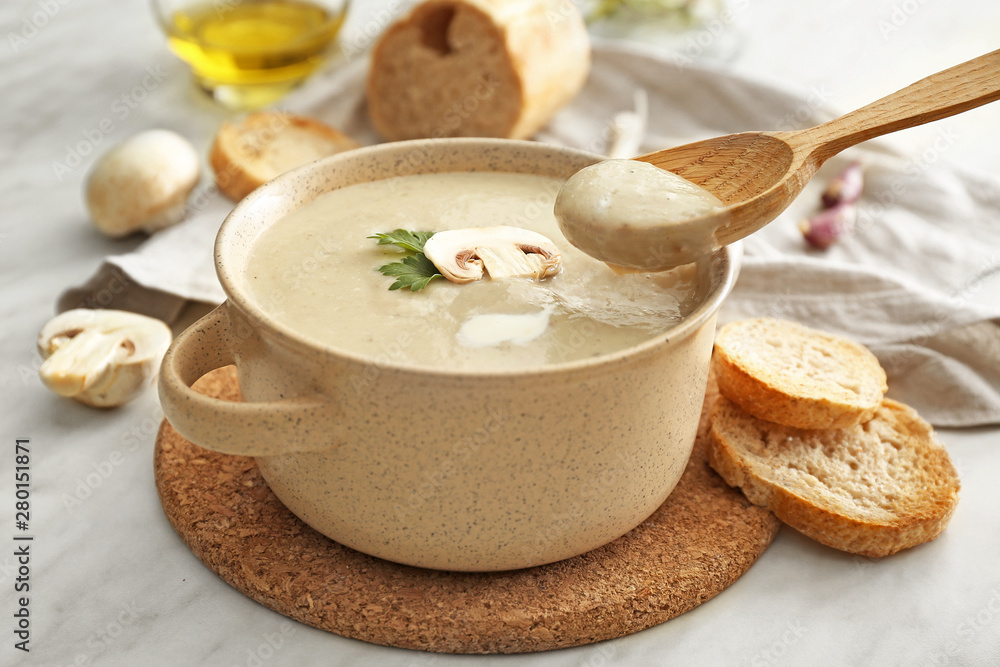 Pot of tasty mushroom cream soup on table