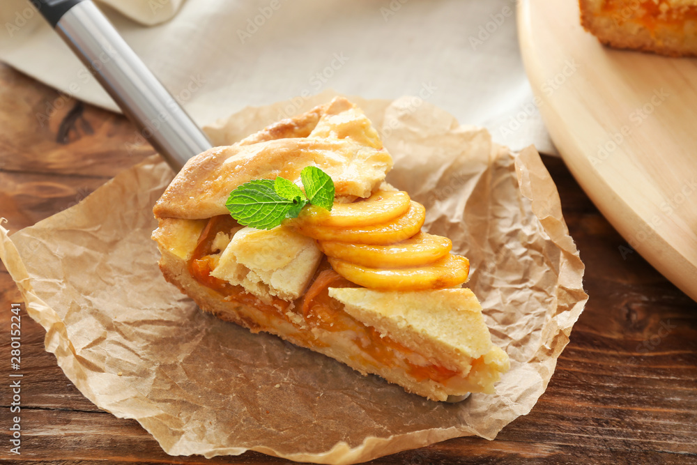 Piece of tasty peach pie on wooden background