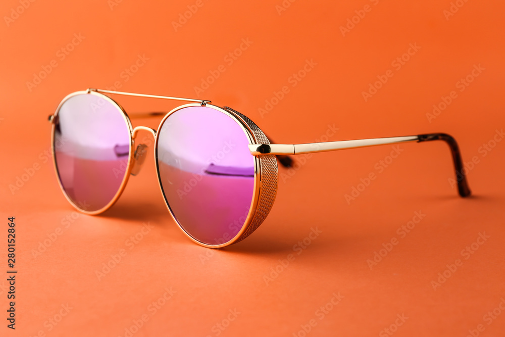 Modern sunglasses on color background