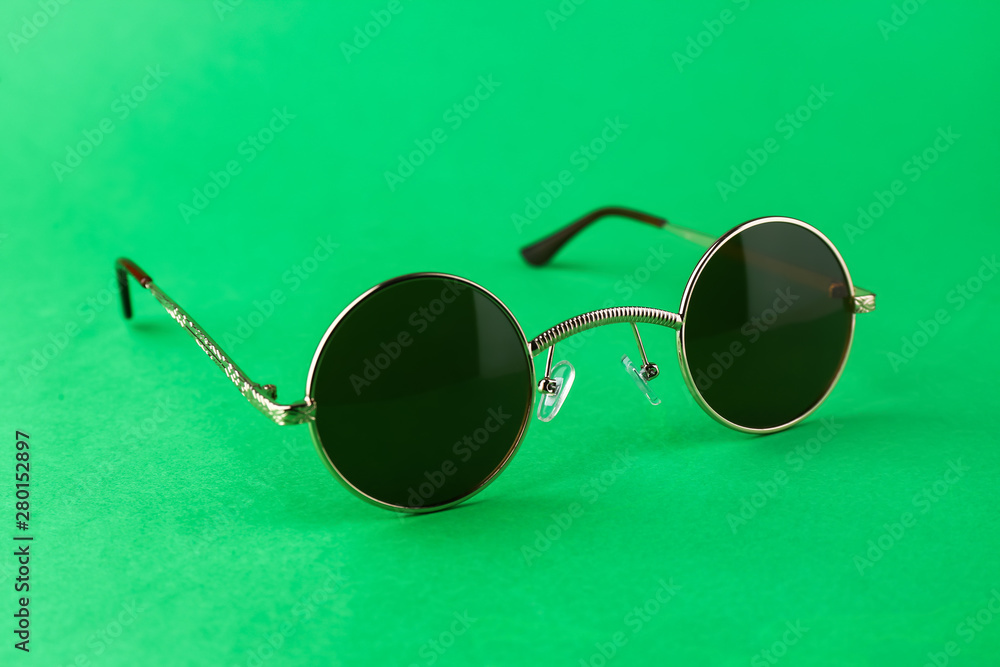 Modern sunglasses on color background