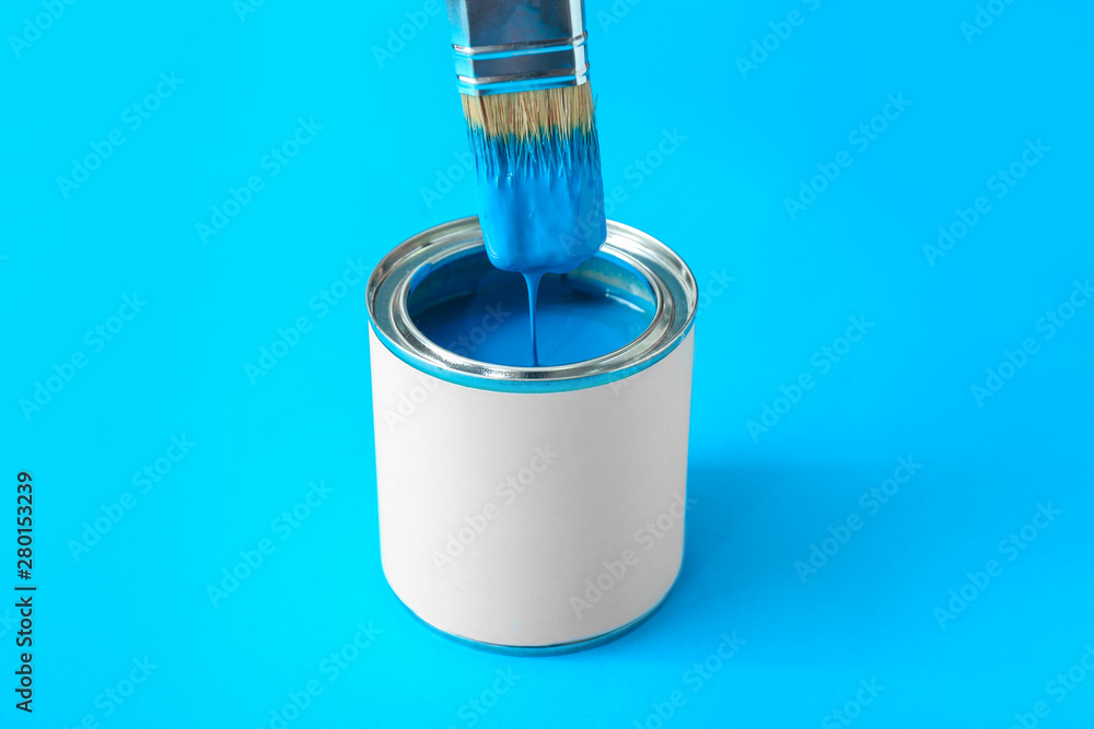 Can of paint and brush on color background