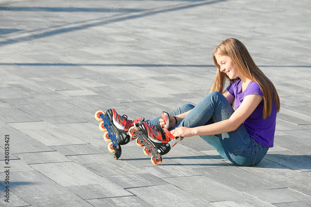 Teenage girl putting on roller skates outdoors