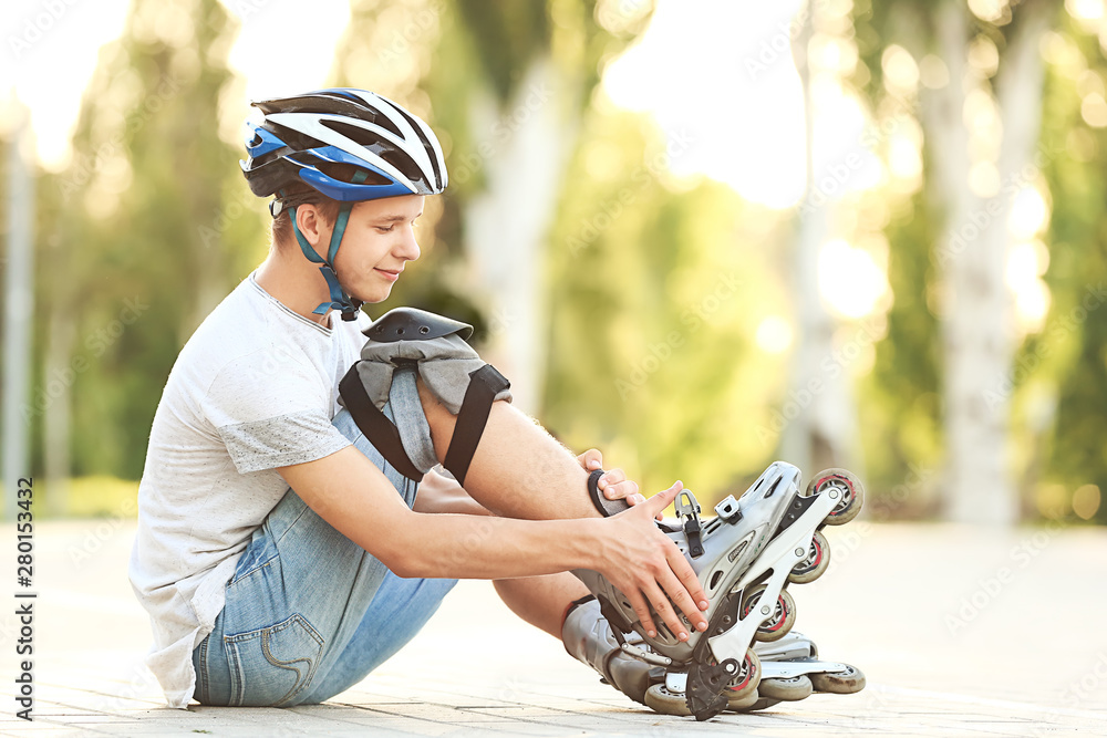 Teenage boy putting on roller skates outdoors