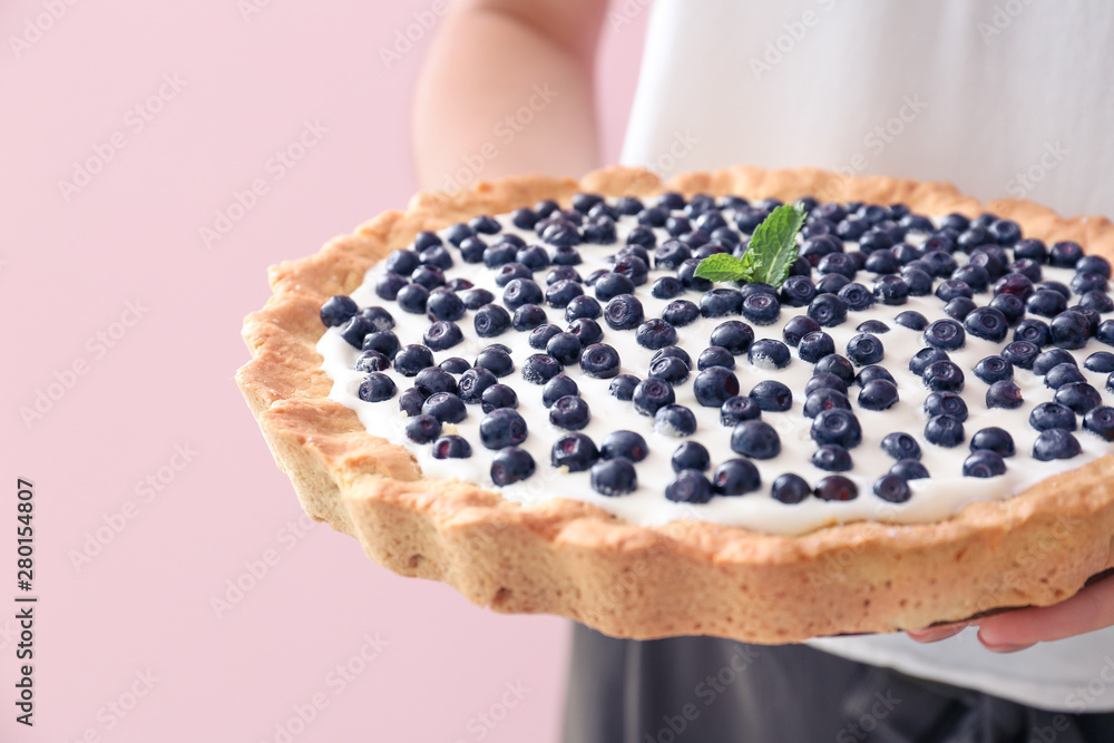 Woman with tasty bilberry pie on color background, closeup