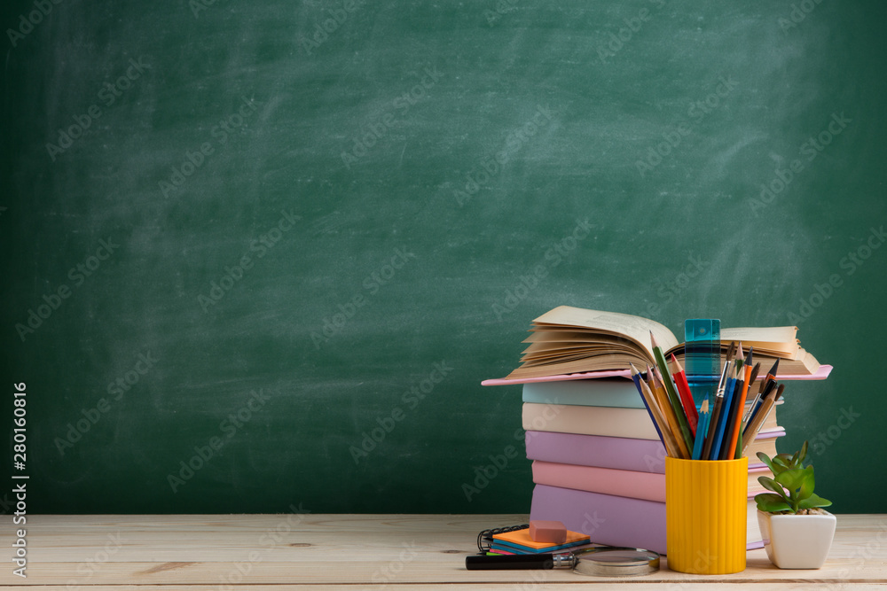 Education and reading concept - group of colorful books on the wooden table in the classroom, blackb