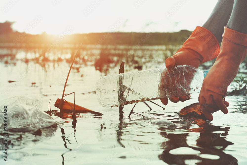 hand picking up garbage plastic for cleaning in river