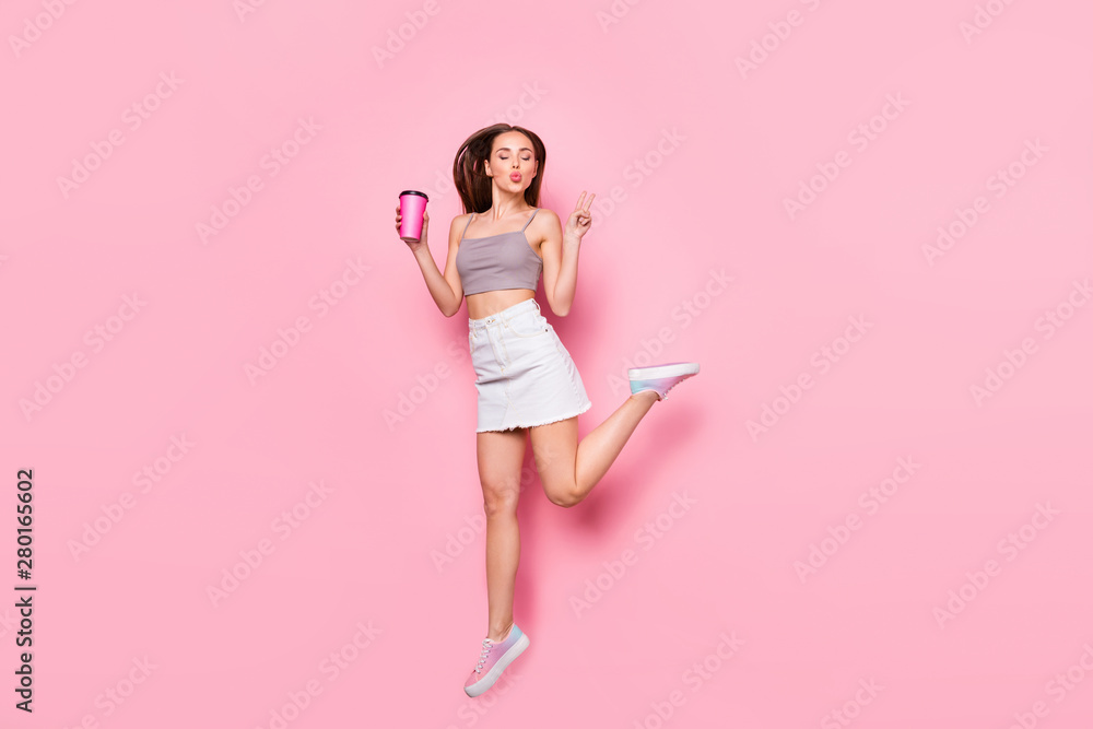 Full length photo of cute youth jumping making v-signs holding mug with hot beverage sending air kis