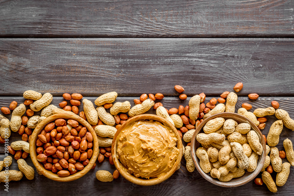 Make peanut butter with paste in glass bowl on wooden background top view copyspace