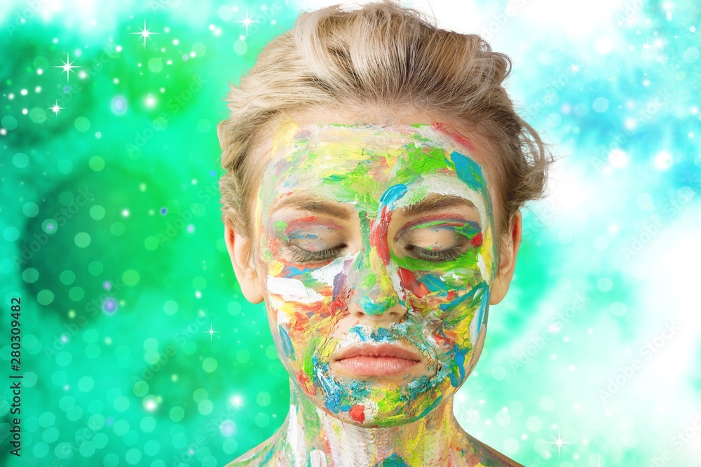 Young beautiful woman with painted  face and paintbrushes