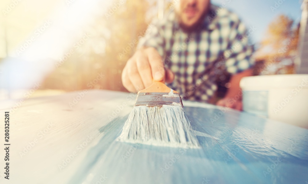 Man with paintbrush in hand and painting on the wooden board