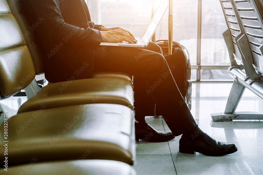 Elegant asian businessman checking email on mobile phone while walking with suitcase inside airport,