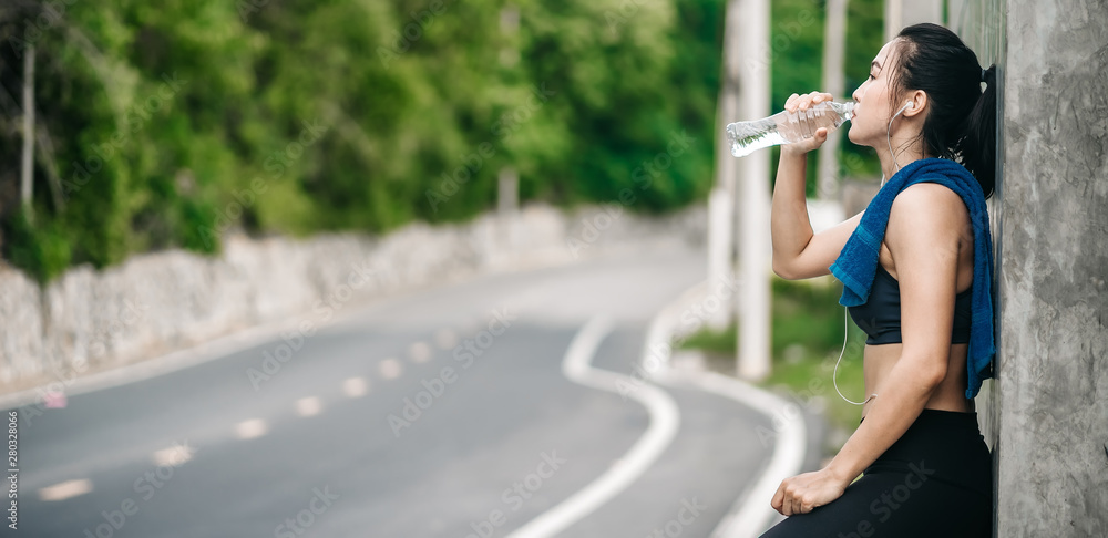 An beautiful Asian woman running and listening music over road during moring. Workout and sport outd