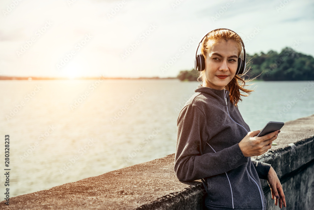 一位亚洲女性早上在锻炼和跑步，她在听智能手机里的音乐。嘿