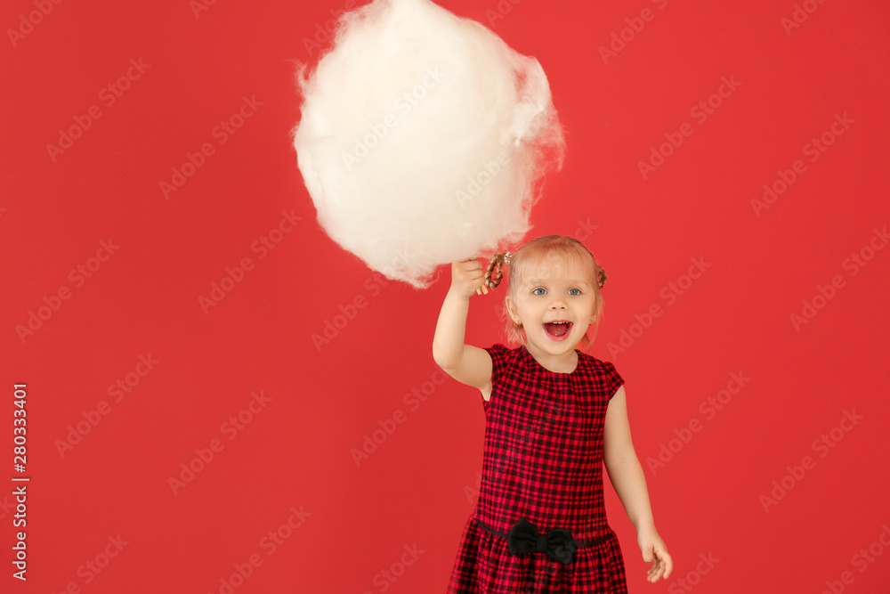 Cute little girl with cotton candy on color background