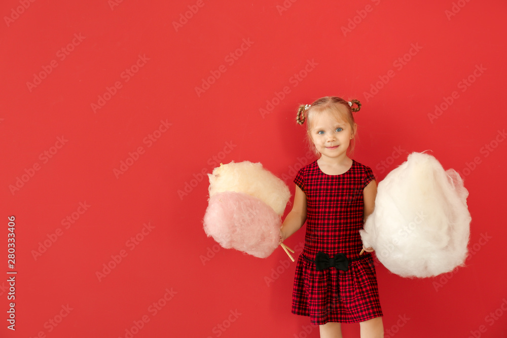 Cute little girl with cotton candy on color background