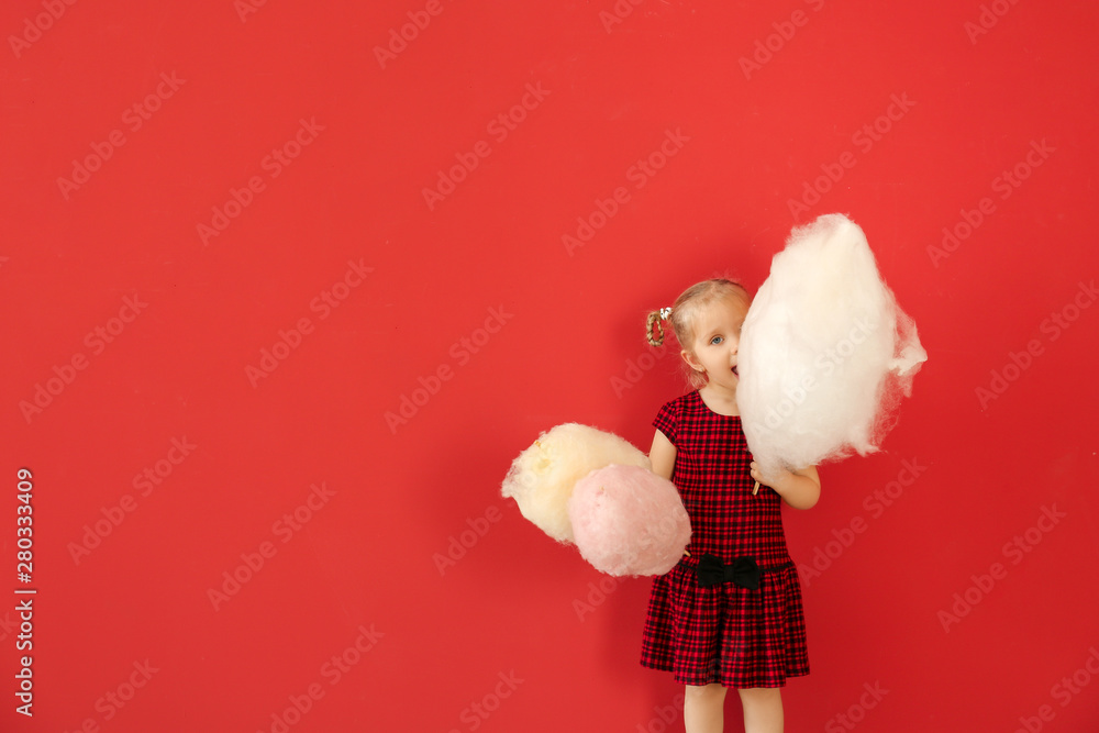 Cute little girl with cotton candy on color background