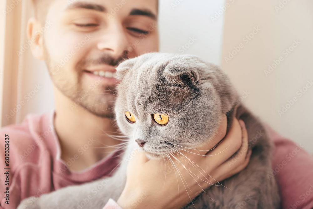 Young man with cute funny cat at home