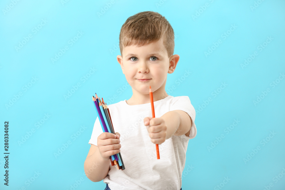 Cute little boy with pencils on color background