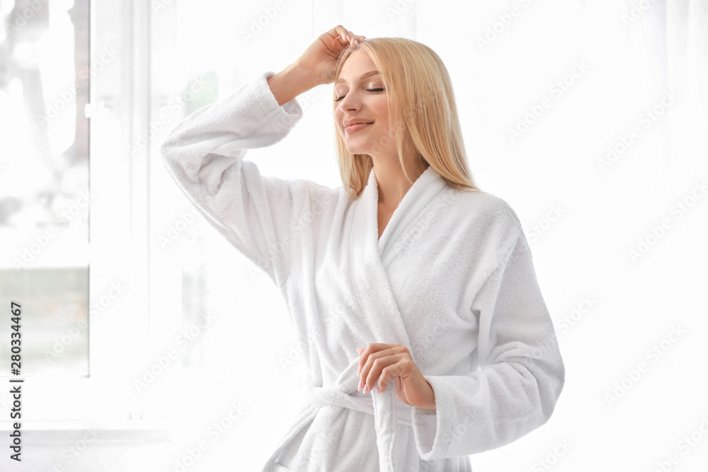 Beautiful young woman in bathrobe at home