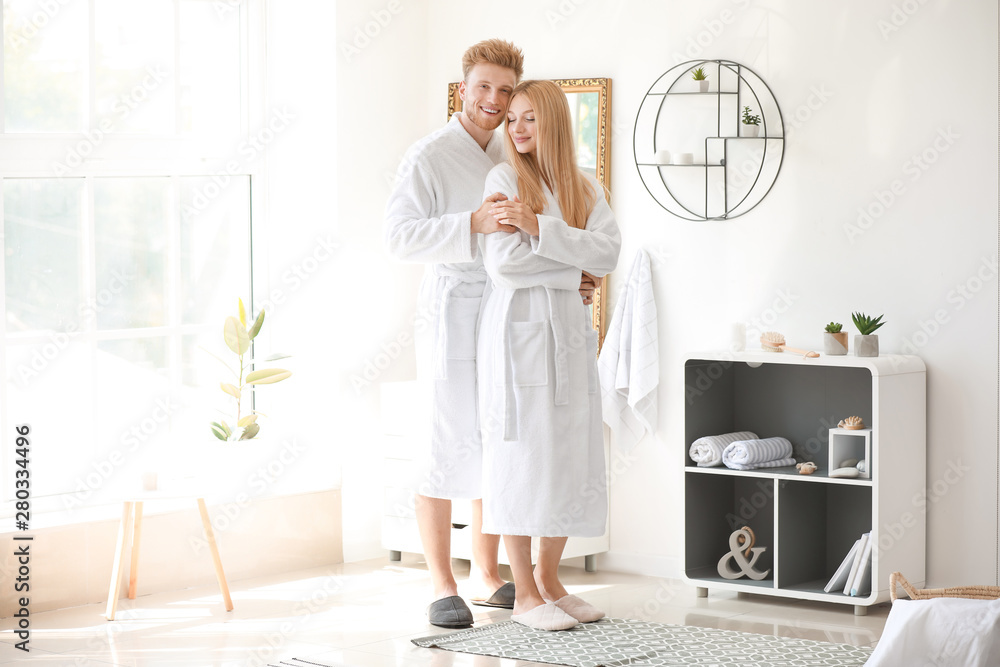 Morning of happy young couple in bathrobes at home