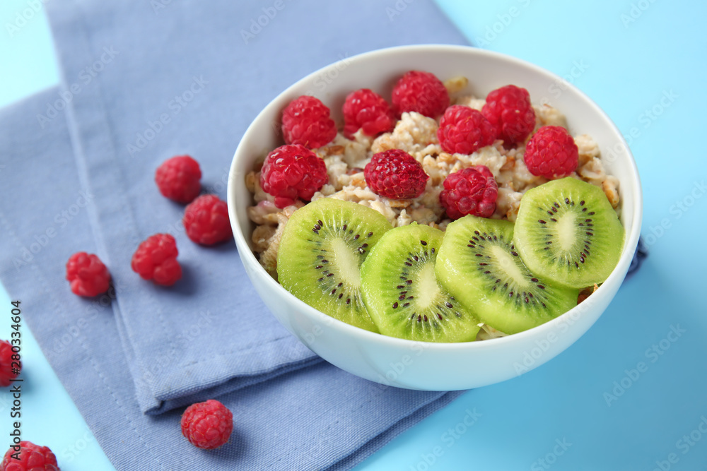 Bowl with tasty sweet oatmeal on color background