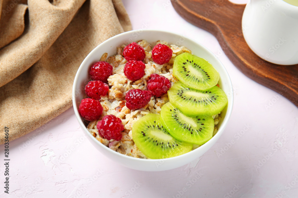 Bowl with tasty sweet oatmeal on light table