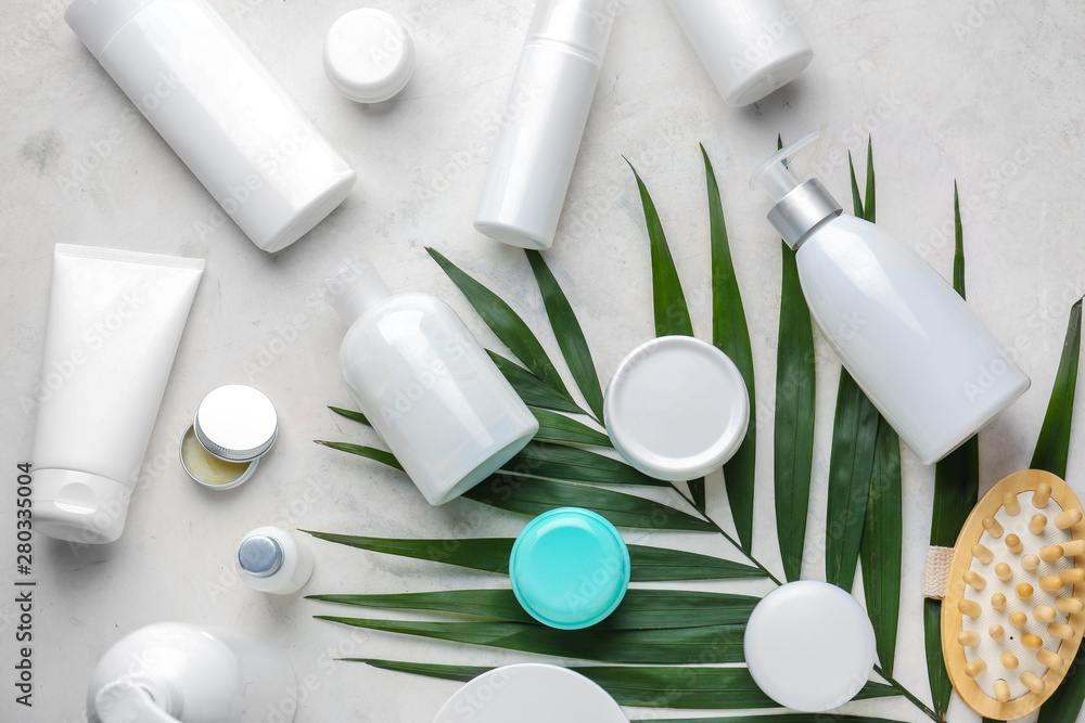 Set of cosmetic products and palm leaf on light background