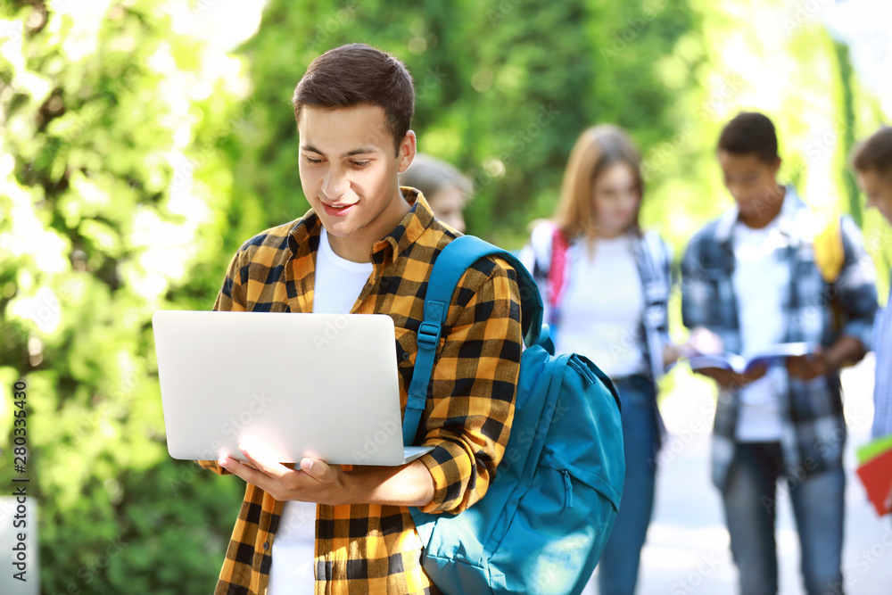 Young student with laptop outdoors