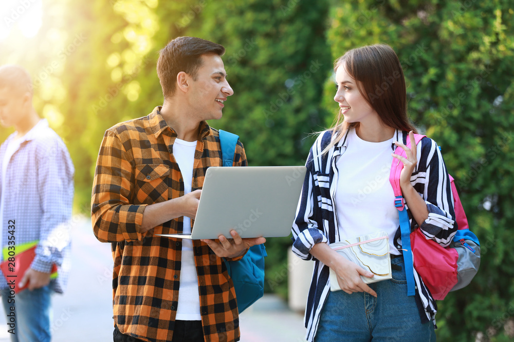 Young students with laptop outdoors