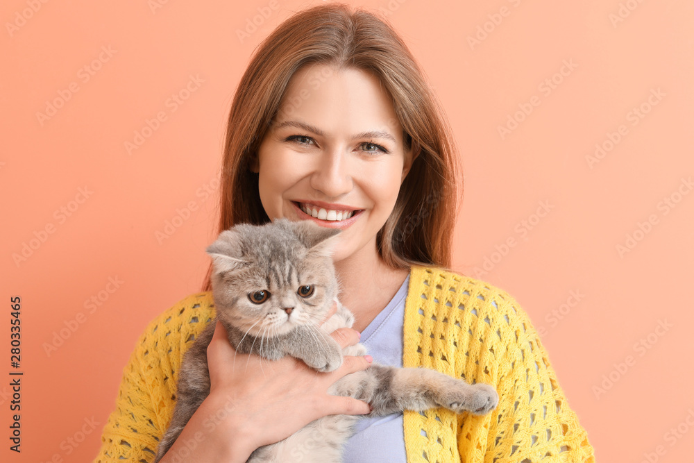 Beautiful young woman with cute cat on color background