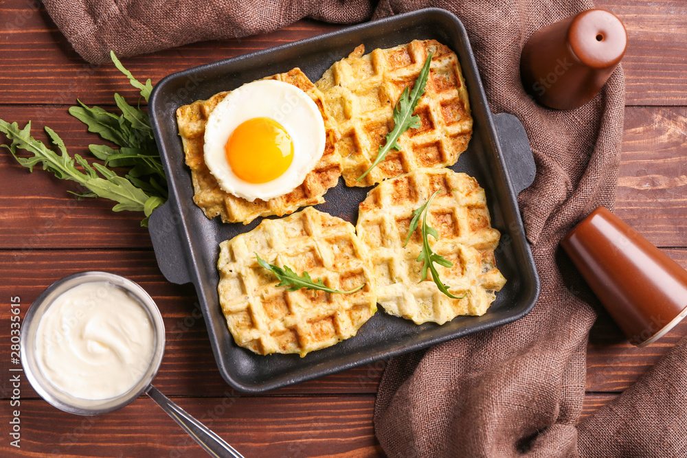 Frying pan with tasty squash waffles and fried egg on table