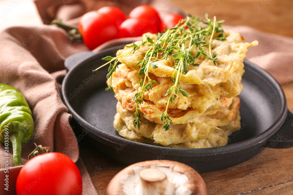 Frying pan with tasty squash waffles on table