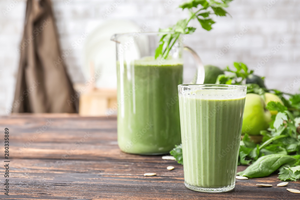 Glass and jug of healthy smoothie on table