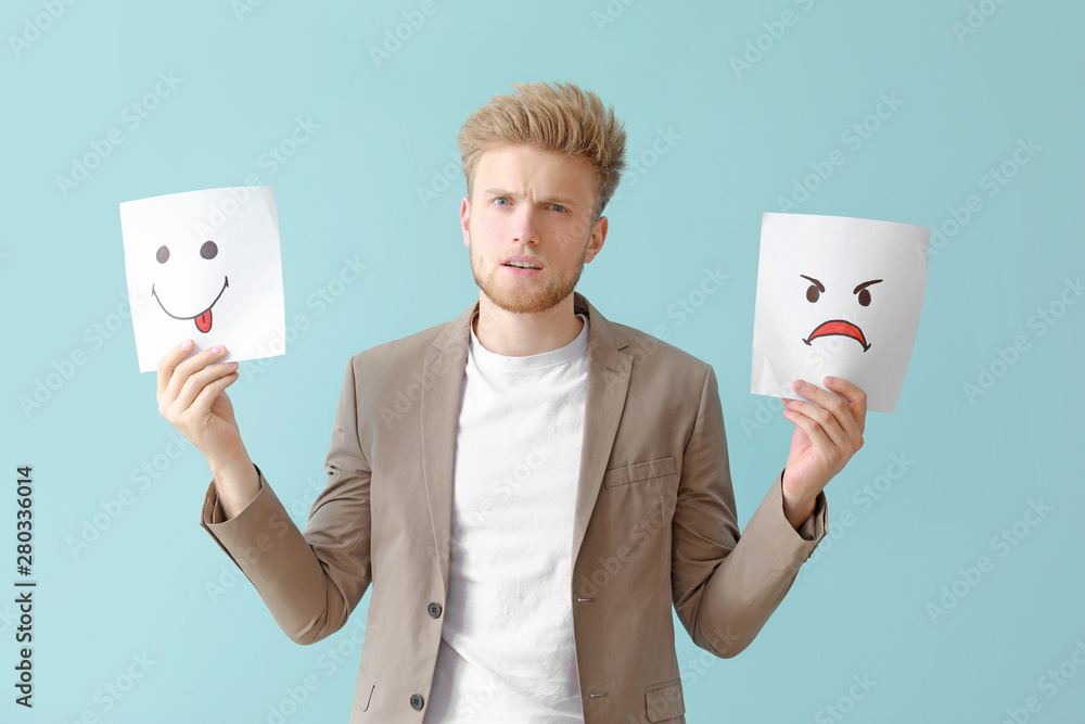 Confused man with emoticons on color background