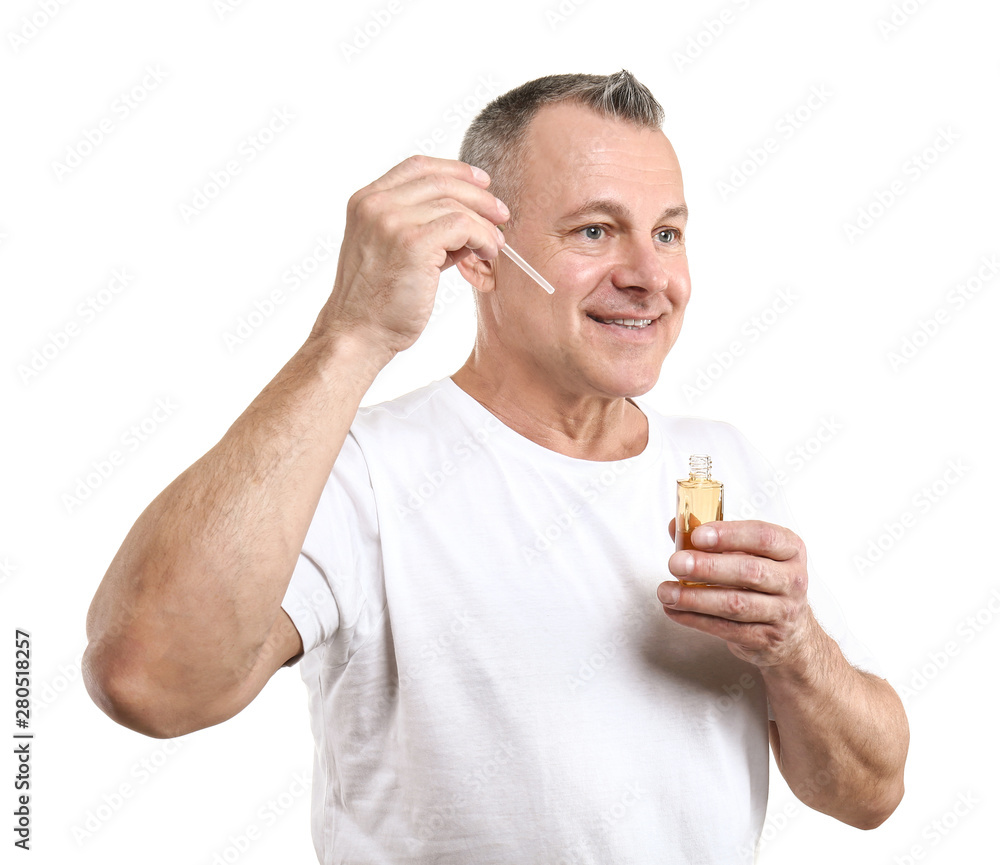 Handsome middle-aged man with bottle of serum for skin care on white background