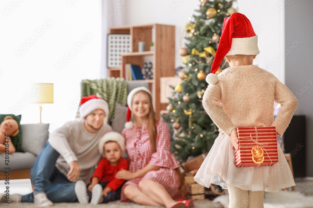 Little girl with gift and her family at home on Christmas eve