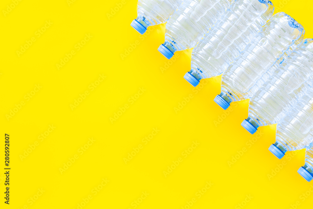 Pure water in plastic bottles on yellow background top view copyspace