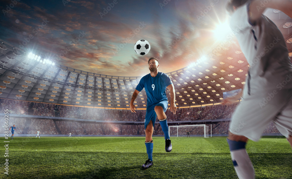 Soccer players in action on professional stadium on sunset.