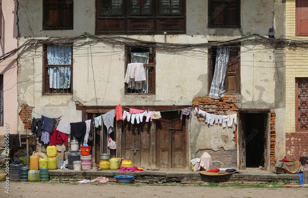 Freshly washed laundry is hung out to dry in front of a decaying house in Nepal.