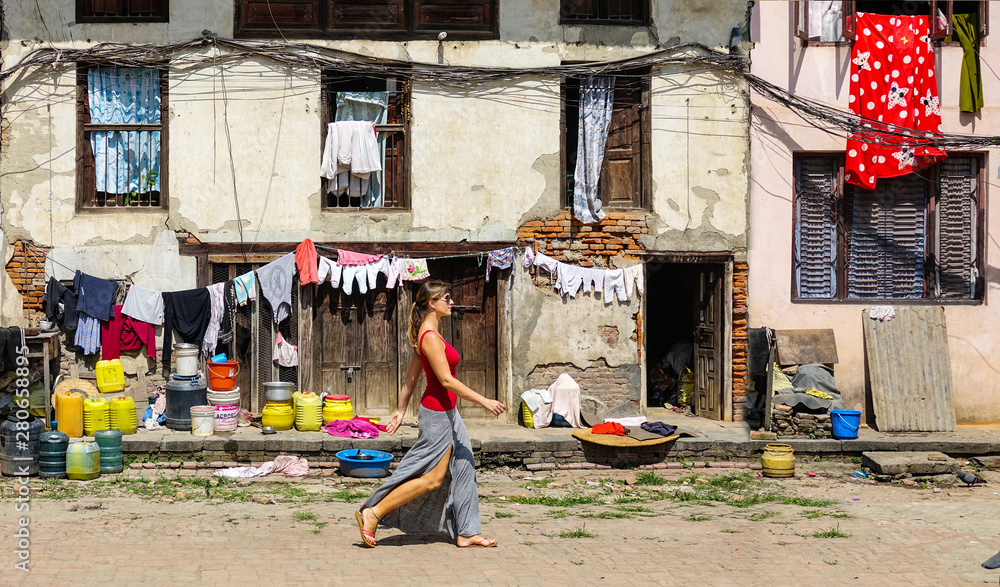 Woman walks past an old deteriorating house in residential part of Kathmandu.